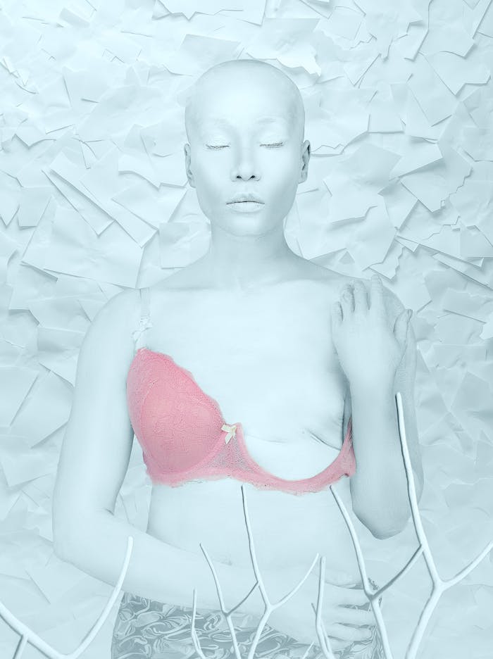 Expressive artistic portrait of a woman with closed eyes wearing a pink brassiere, symbolizing resilience and beauty.