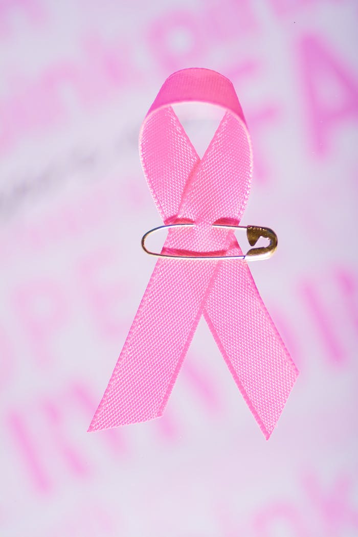 Close-up of pink ribbon with safety pin for breast cancer awareness.