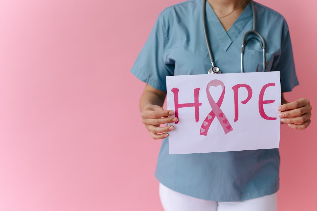 contact-img Doctor holding a 'Hope' sign advocating breast cancer awareness with a pink background.