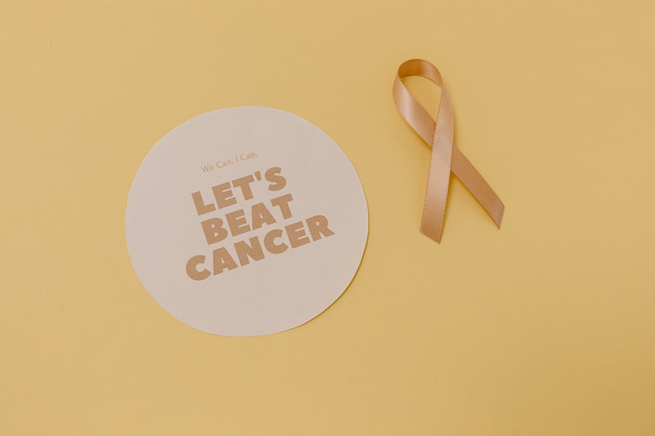 Flatlay of a cancer awareness ribbon and motivational message, promoting cancer support.