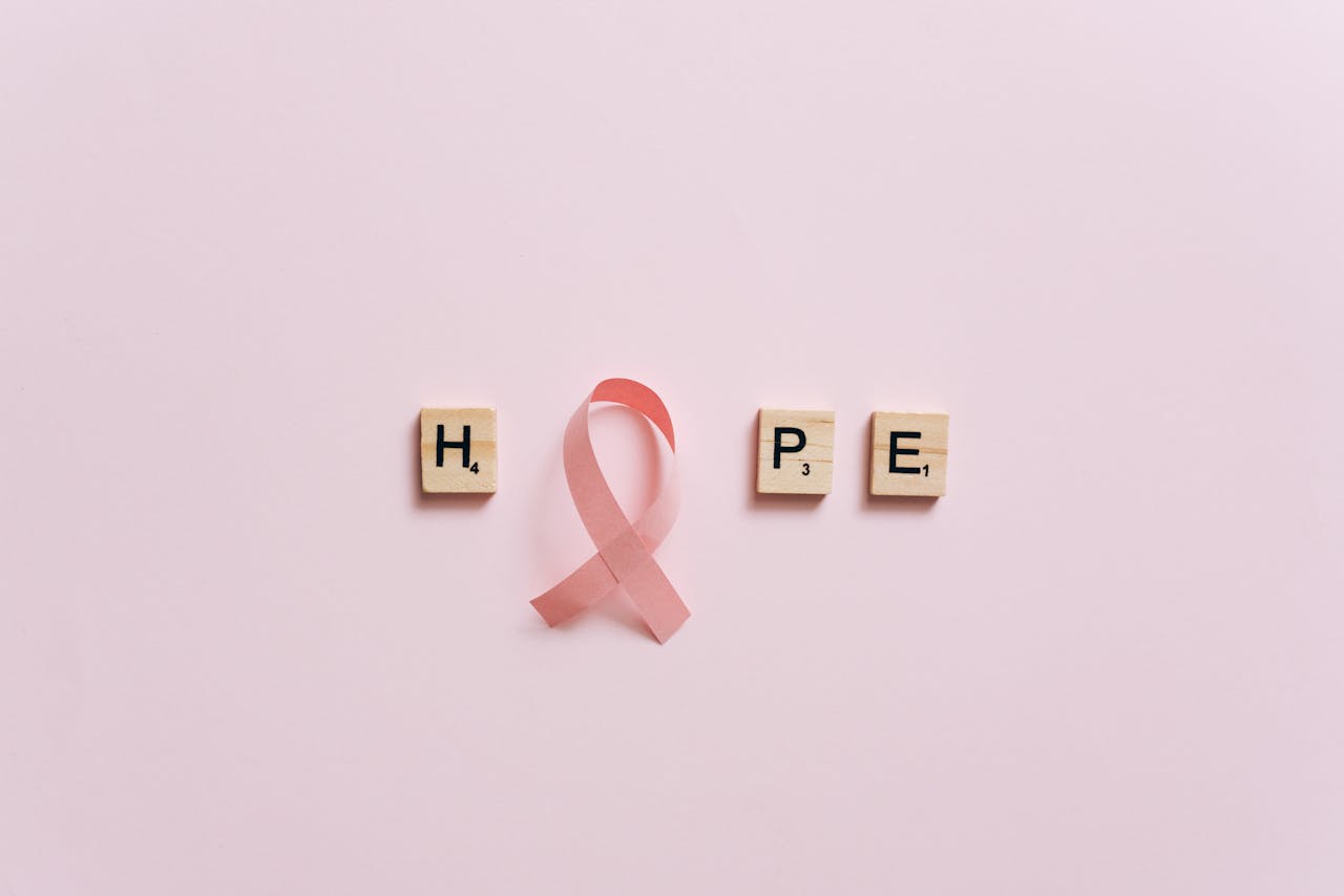 services-img Flat lay of pink ribbon symbolizing cancer awareness with scrabble tiles spelling HOPE on a pink surface.