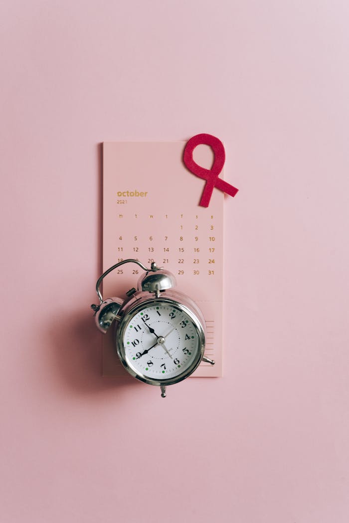Conceptual image of a clock with a pink ribbon and October calendar for breast cancer awareness.