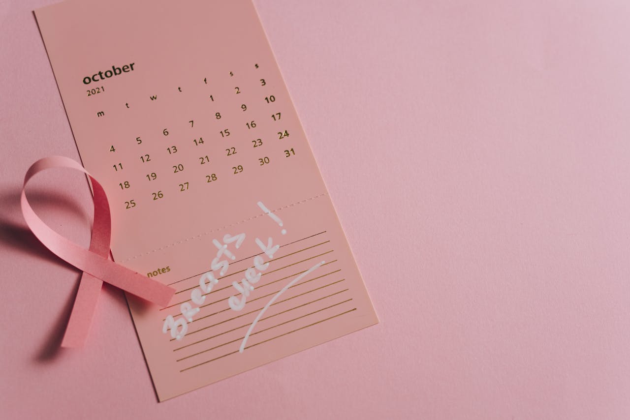 Pink ribbon on a calendar page for Breast Cancer Awareness, focused on health reminder in October.