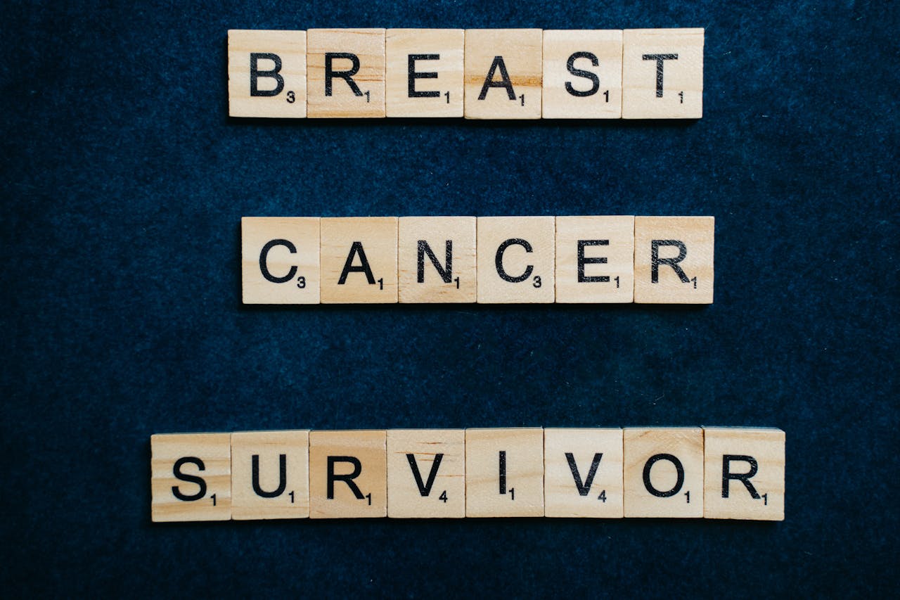 Wooden letter tiles spelling out 'Breast Cancer Survivor' on a dark background.