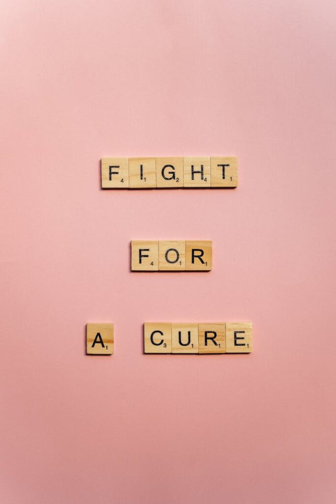 Wooden letter blocks spell 'Fight for a Cure' on a pink background promoting cancer awareness.
